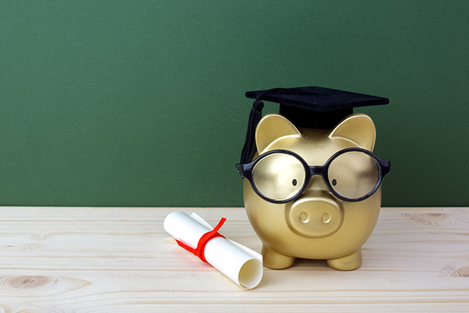 Piggy bank in glasses with diploma and graduation cap