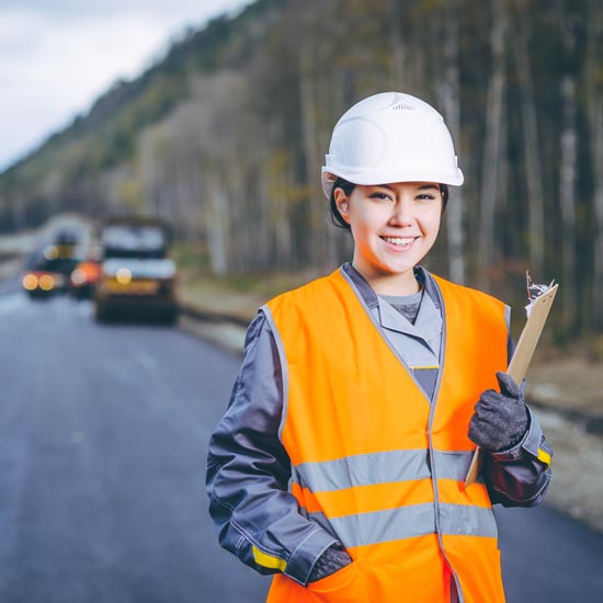 Young woman in PPE holding clipboard during roadwork
