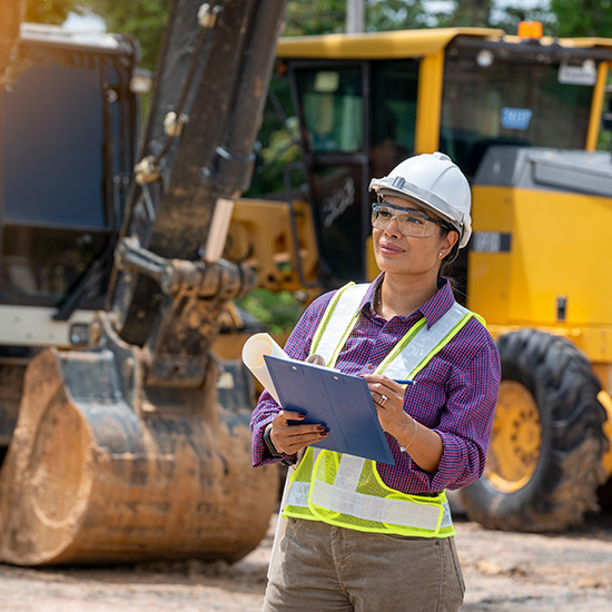 Woman in hard hat and safety vest surveying worksite
