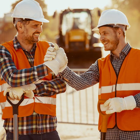 Two construction workers holding shovels and high fiving